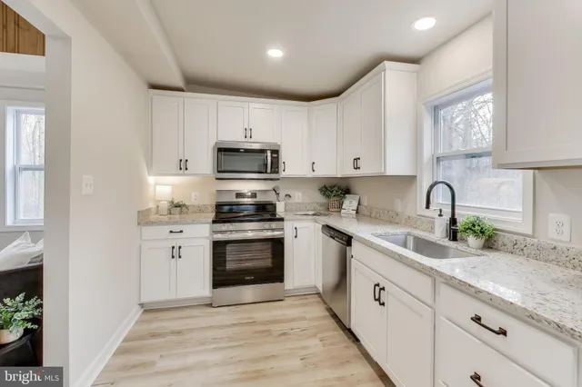 a kitchen with granite countertop a sink stainless steel appliances and cabinets