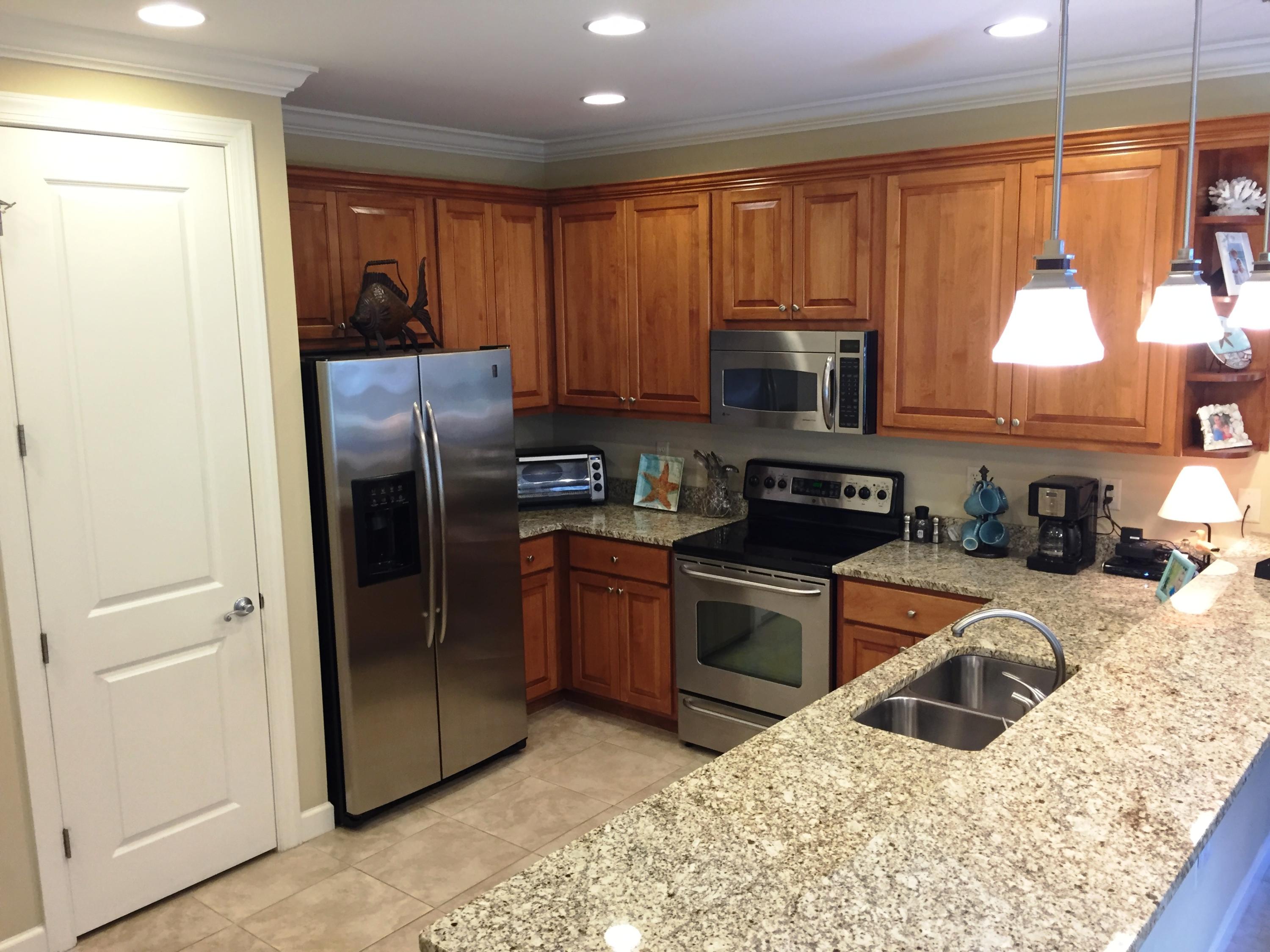 136 South Zander Way Santa Rosa Beach, FL 32459 - Photo 5 of 27 a kitchen with granite countertop wooden cabinets a refrigerator and a sink