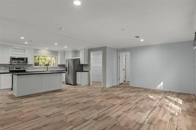 a view of kitchen with kitchen island refrigerator sink and white cabinets