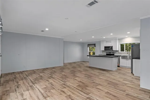 a view of kitchen with kitchen island a sink wooden floor and a counter top space