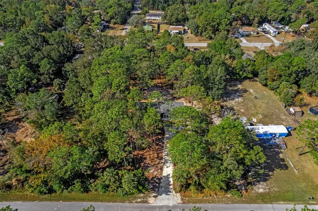 an aerial view of residential house with outdoor space and trees all around