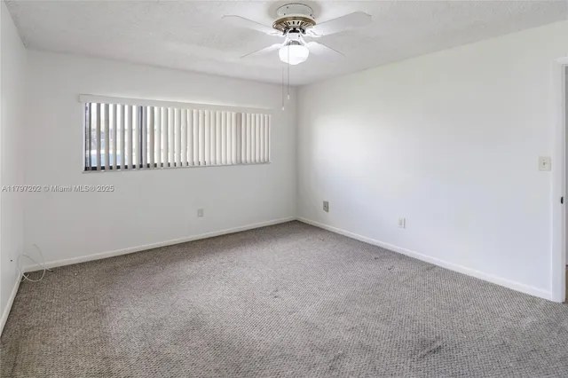 an empty room with a window and a ceiling fan