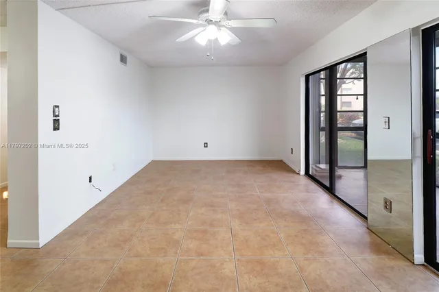 an empty room with chandelier fan and windows