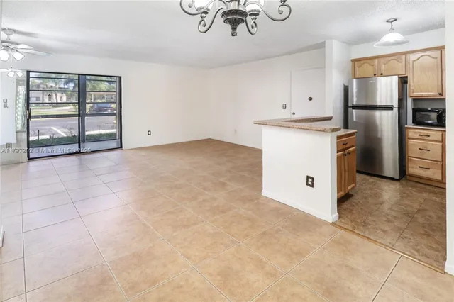 a view of kitchen with refrigerator cabinets and windows