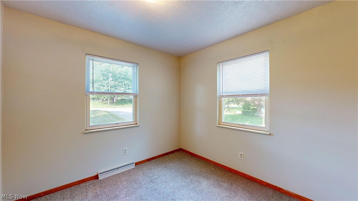 3394 Waterloo Road Mogadore, OH 44260 - Photo 24 of 40 Unfurnished room with a baseboard heating unit, a healthy amount of sunlight, a textured ceiling, and carpet