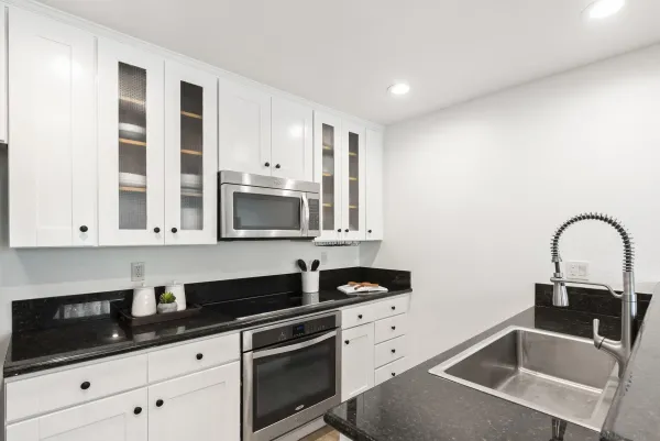 a kitchen with granite countertop a sink a stove and cabinets