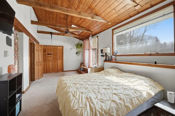 a bed sitting in a spacious bedroom next to a window