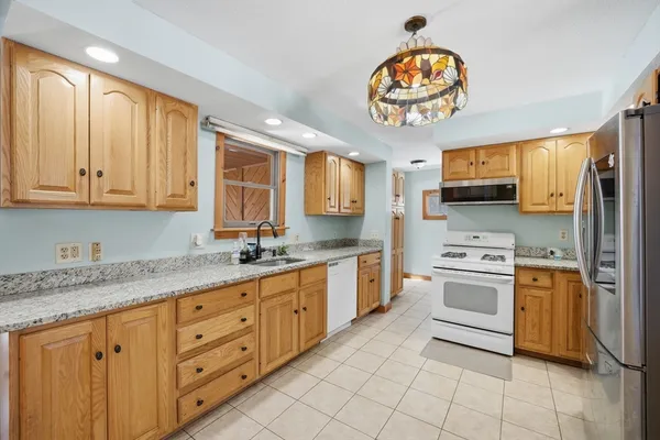 a kitchen with stainless steel appliances granite countertop a stove a sink dishwasher and a refrigerator