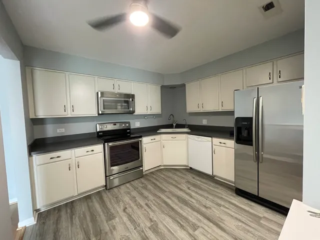 a kitchen with granite countertop a refrigerator stove top oven and sink