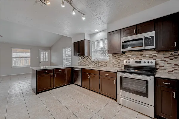 a kitchen with stainless steel appliances granite countertop wooden cabinets a stove top oven a sink and dishwasher