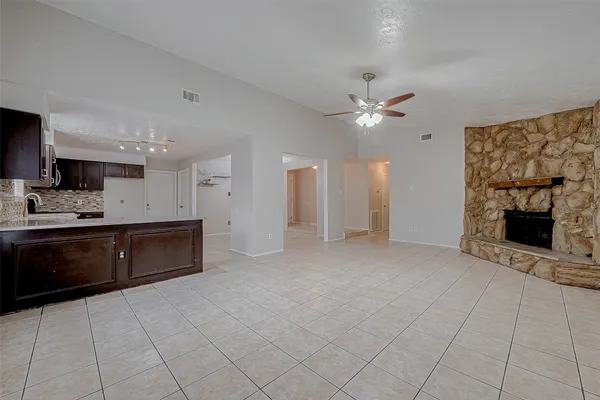 a view of an empty room with a kitchen and a fireplace