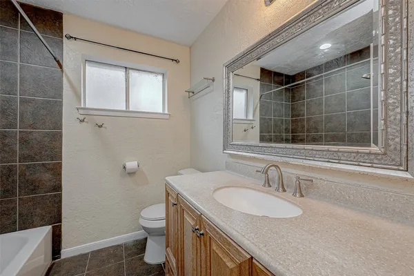 a bathroom with a granite countertop sink a toilet and shower