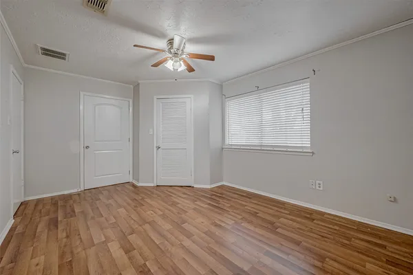 a view of empty room with wooden floor and fan