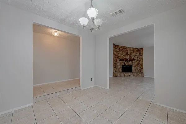 a view of an empty room with a chandelier fan and a window