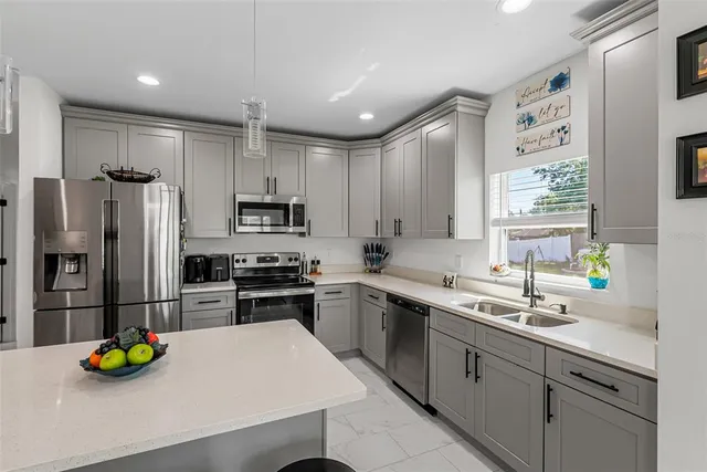 a kitchen with stainless steel appliances kitchen island a stove a refrigerator and a sink