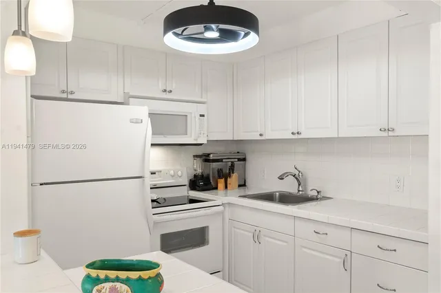 a kitchen with a sink a refrigerator and cabinets