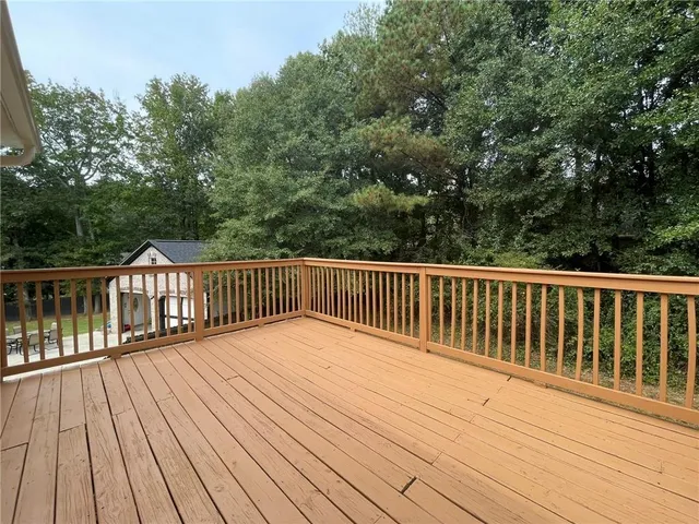 a balcony with wooden floor and trees in the background