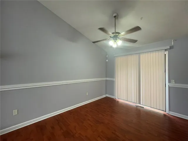 an empty room with wooden floor and fan