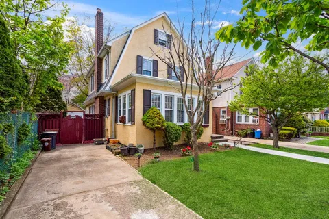 a view of a house with a yard plants and large tree