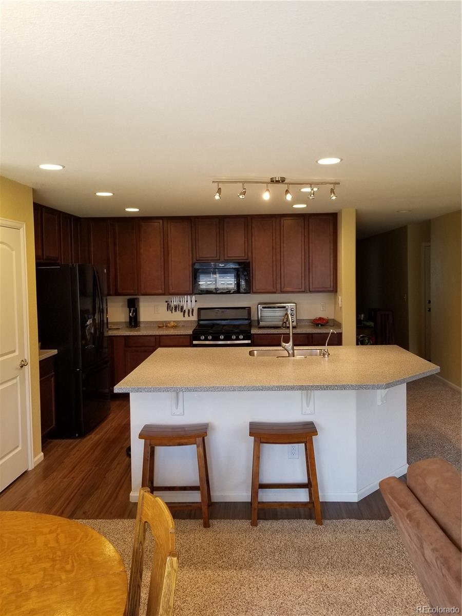 3268 Raintree Lane Dacono, CO 80514 - Photo 12 of 35 a kitchen with kitchen island a cabinets counter top space a sink and appliances