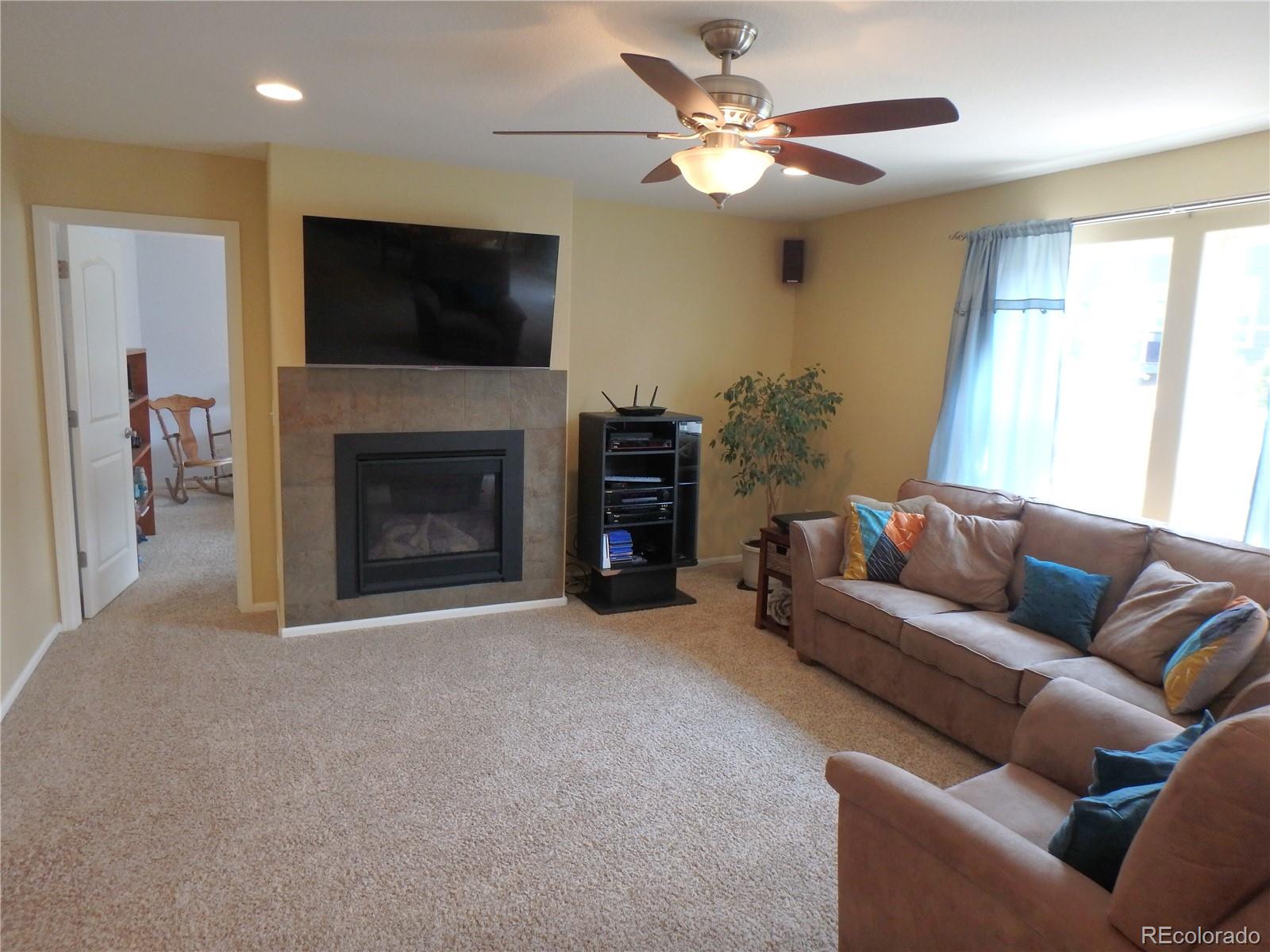 3268 Raintree Lane Dacono, CO 80514 - Photo 14 of 35 a living room with furniture a flat screen tv and a fireplace