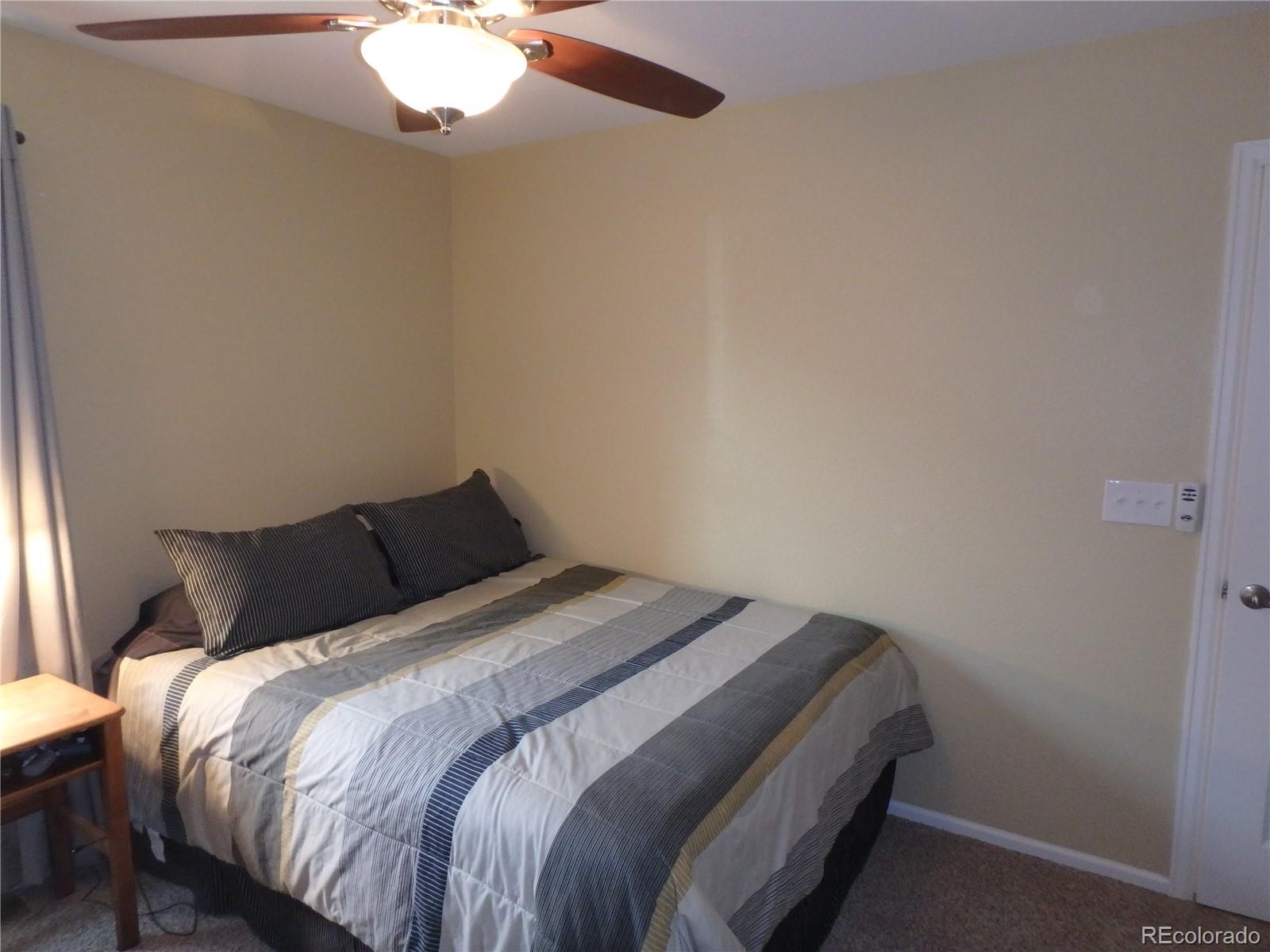 3268 Raintree Lane Dacono, CO 80514 - Photo 16 of 35 a bedroom with a bed and a chandelier