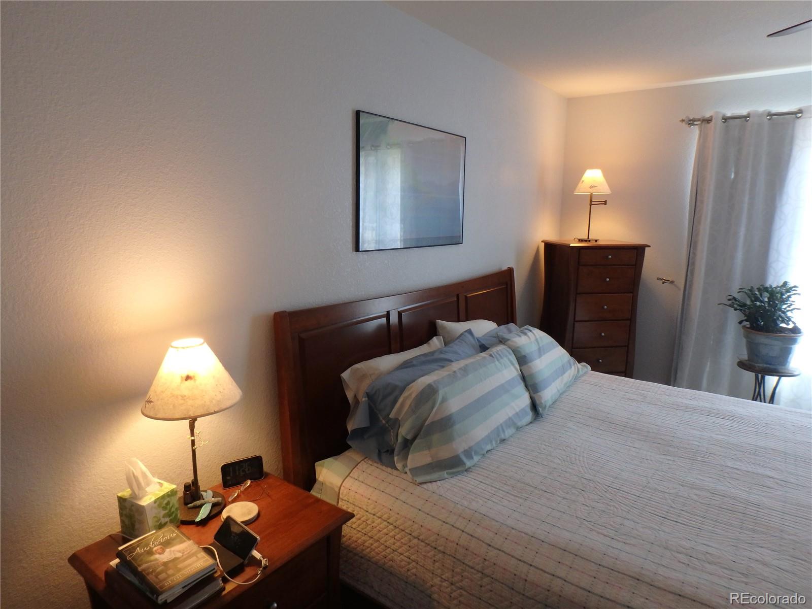 3268 Raintree Lane Dacono, CO 80514 - Photo 18 of 35 a bedroom with a bed and a lamp