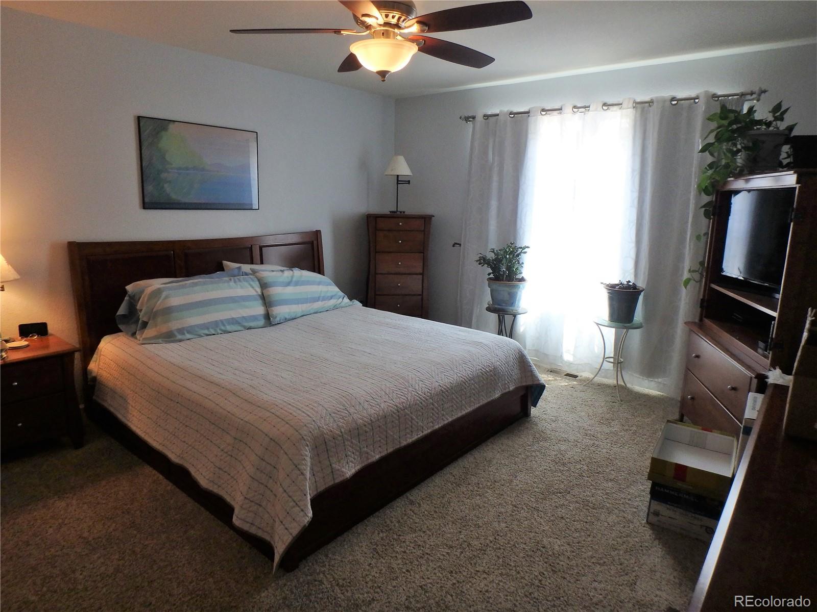 3268 Raintree Lane Dacono, CO 80514 - Photo 19 of 35 a bedroom with a bed and a flat tv screen on a dresser