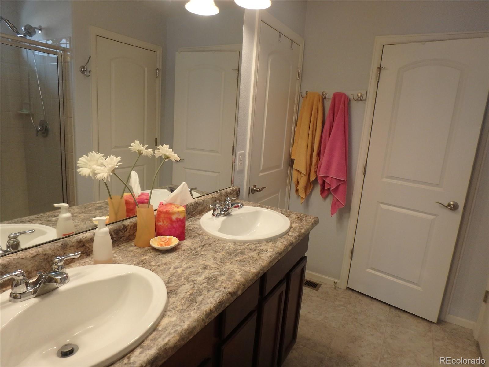 3268 Raintree Lane Dacono, CO 80514 - Photo 21 of 35 a bathroom with a granite countertop sink a mirror and a shower