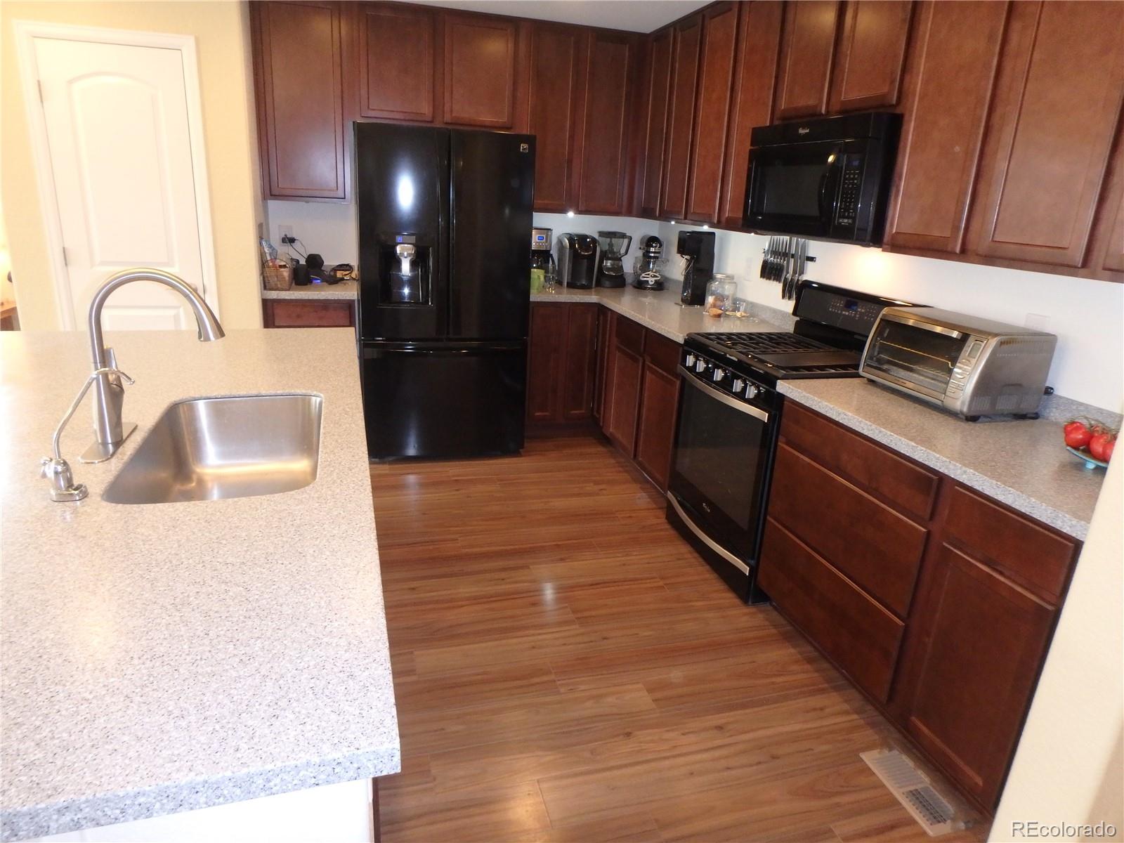 3268 Raintree Lane Dacono, CO 80514 - Photo 7 of 35 a kitchen with a sink and wooden cabinets