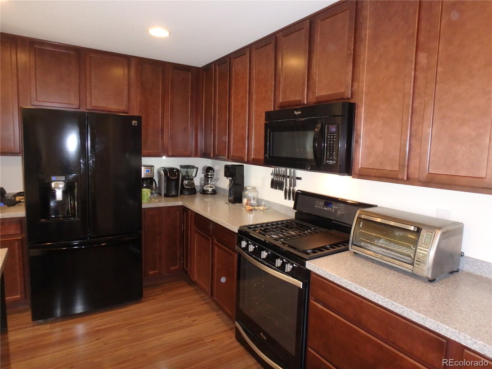 3268 Raintree Lane Dacono, CO 80514 - Photo 8 of 35 a kitchen with wooden cabinets and black appliances