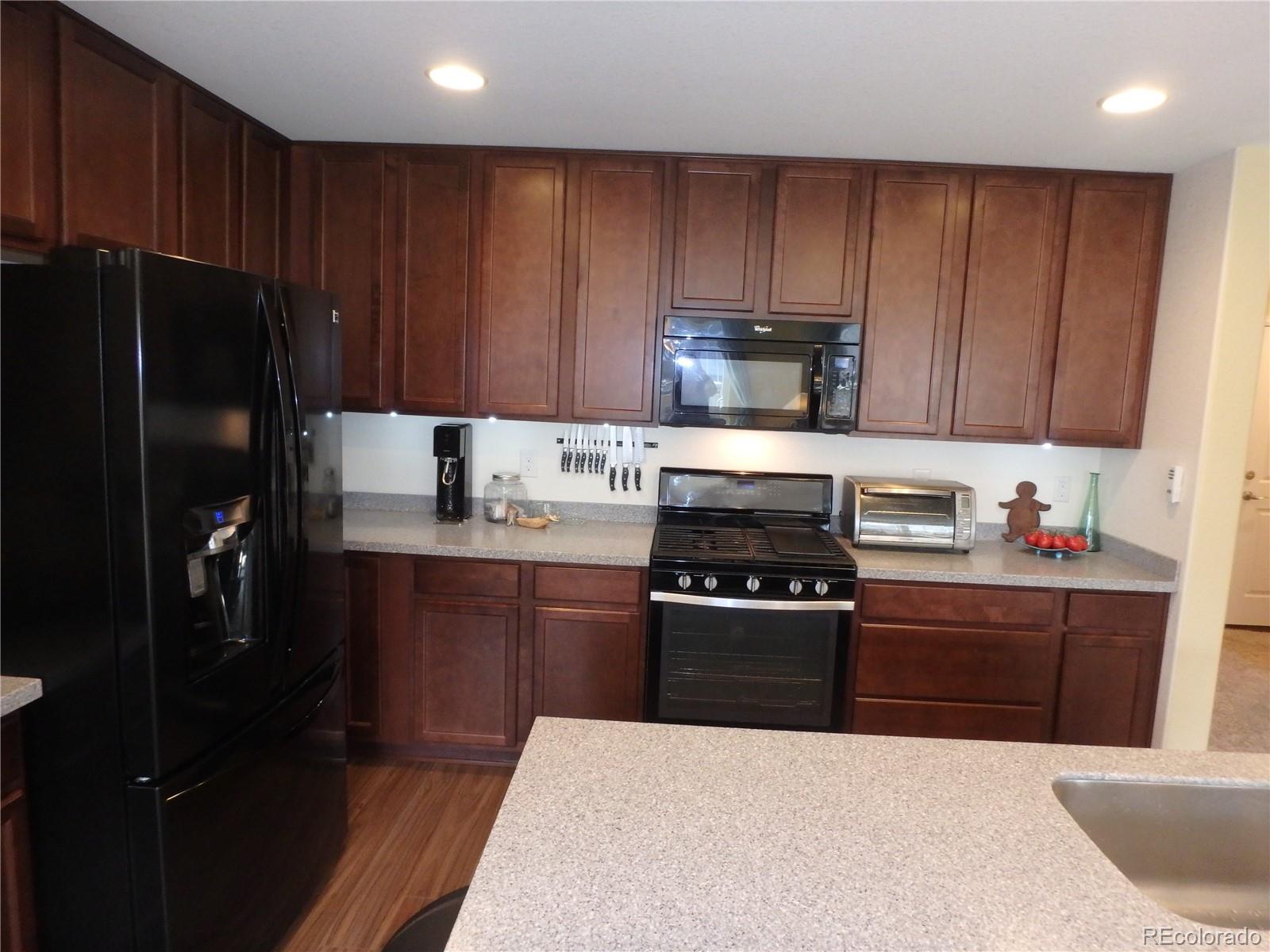 3268 Raintree Lane Dacono, CO 80514 - Photo 9 of 35 a kitchen with wooden cabinets and stainless steel appliances