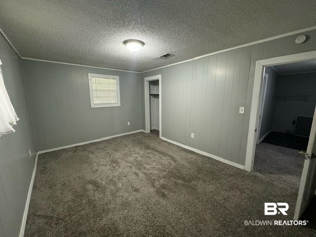 502 Forest Street Mobile, AL 36611 - Photo 7 of 10 Unfurnished bedroom with a closet, a spacious closet, dark colored carpet, and a textured ceiling