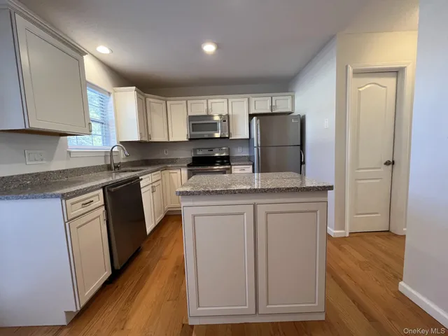 a kitchen with granite countertop a refrigerator stove top oven and sink