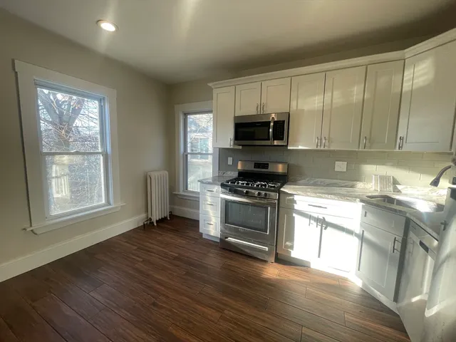 a kitchen with granite countertop a stove a sink and a microwave