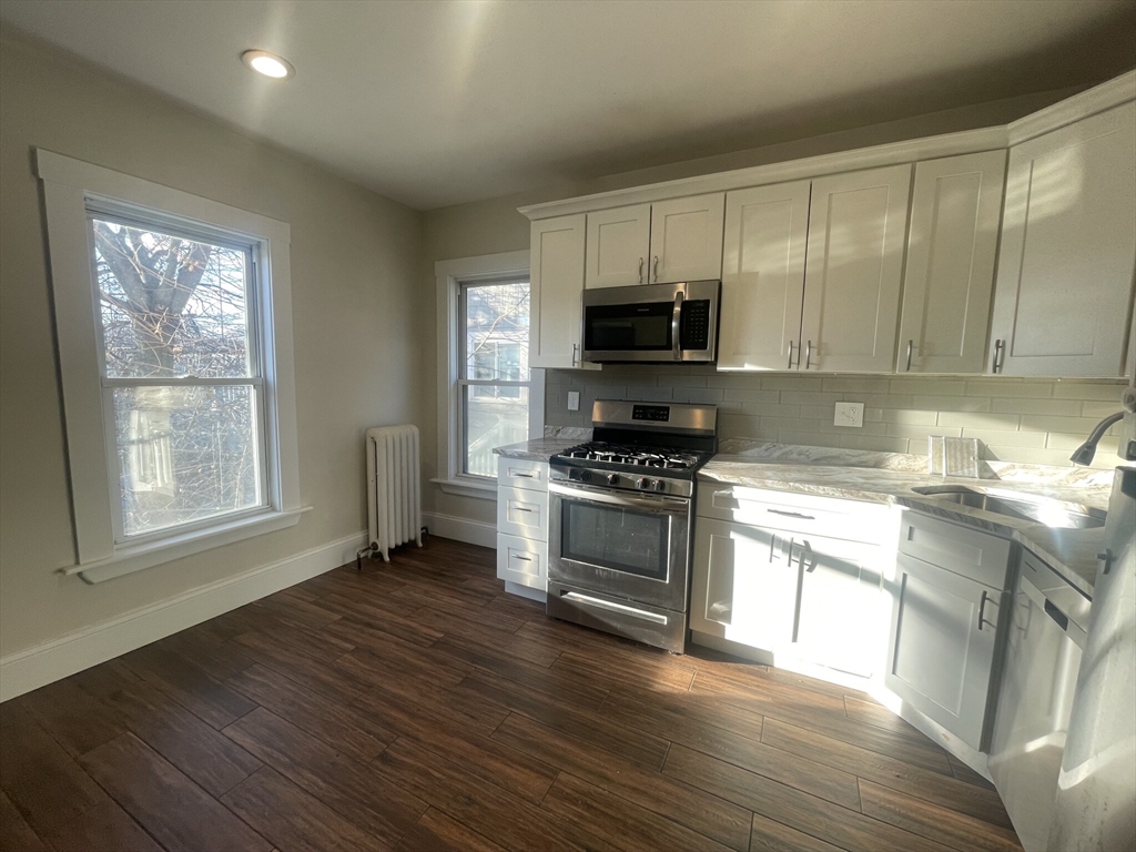 a kitchen with granite countertop a stove a sink and a microwave