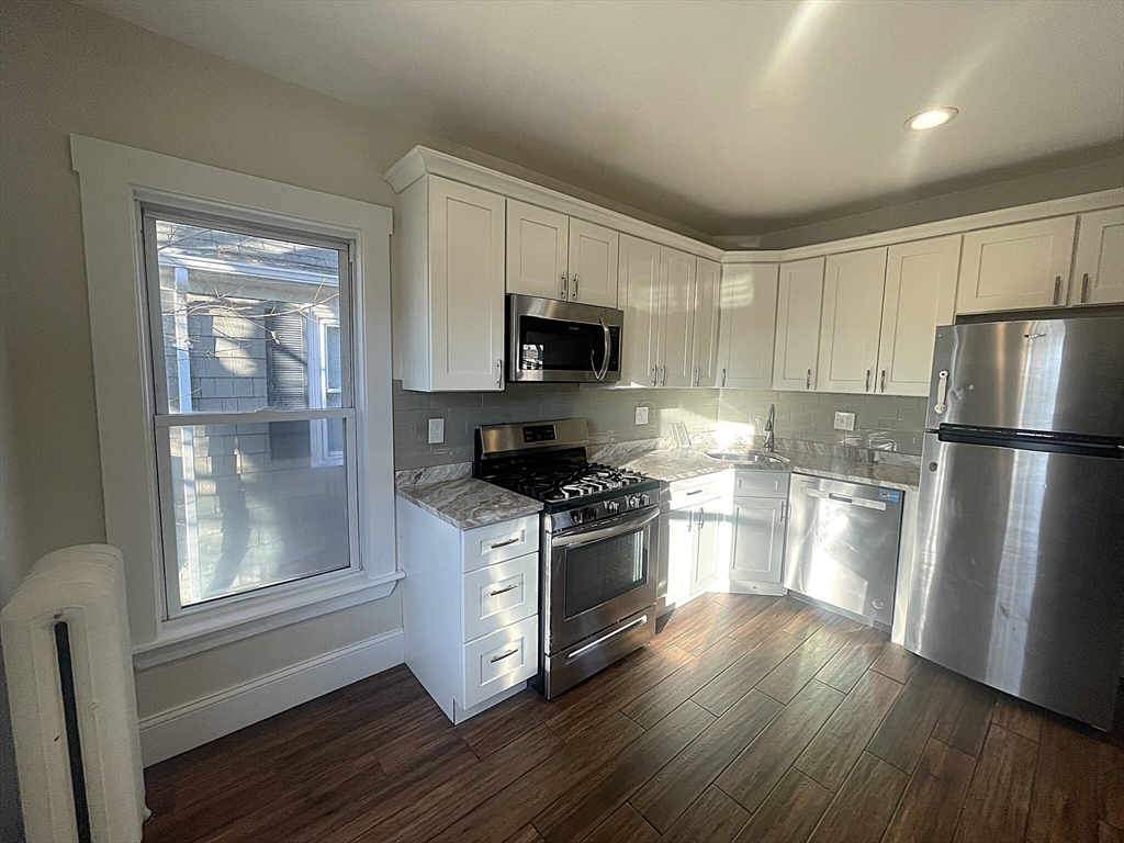 22 Mansfield Street, Unit 2 Boston, MA 02134 - Photo 2 of 18 a kitchen with a refrigerator stove and wooden cabinets