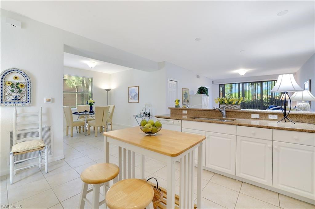 10049 Heather Lane, Unit 101 Naples, FL 34119 - Photo 12 of 25 a kitchen with a sink and chairs