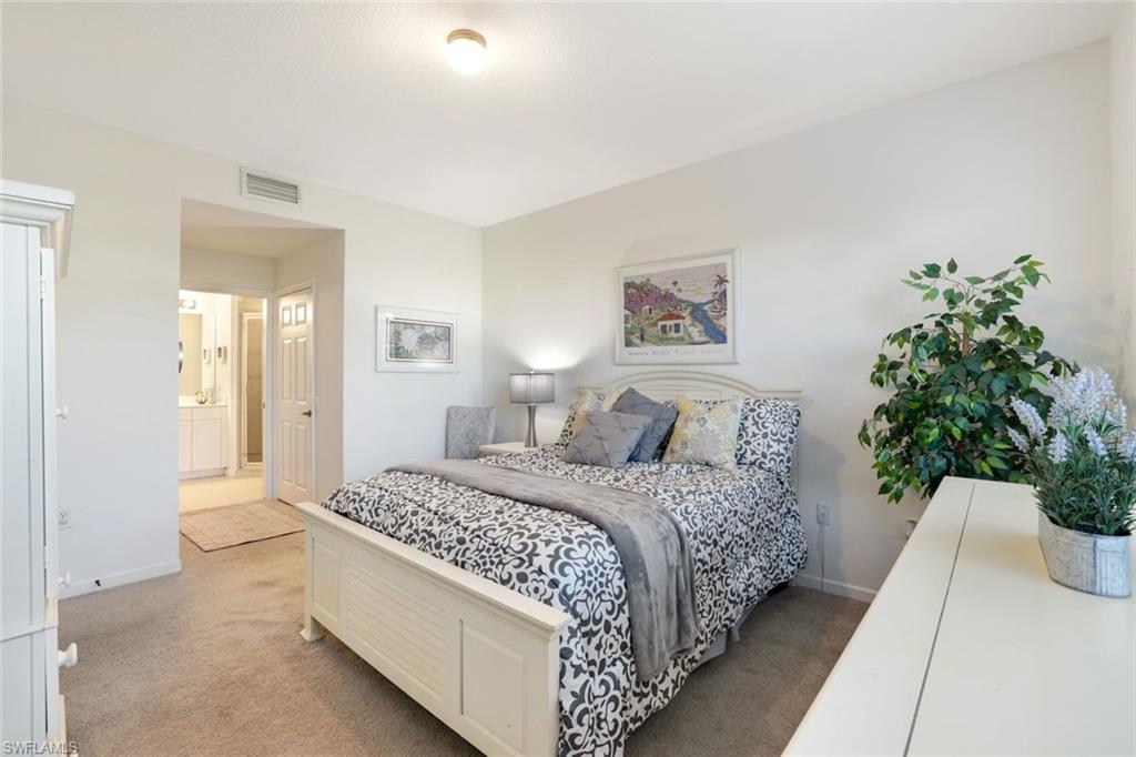 10049 Heather Lane, Unit 101 Naples, FL 34119 - Photo 15 of 25 a bedroom with a large bed and a potted plant