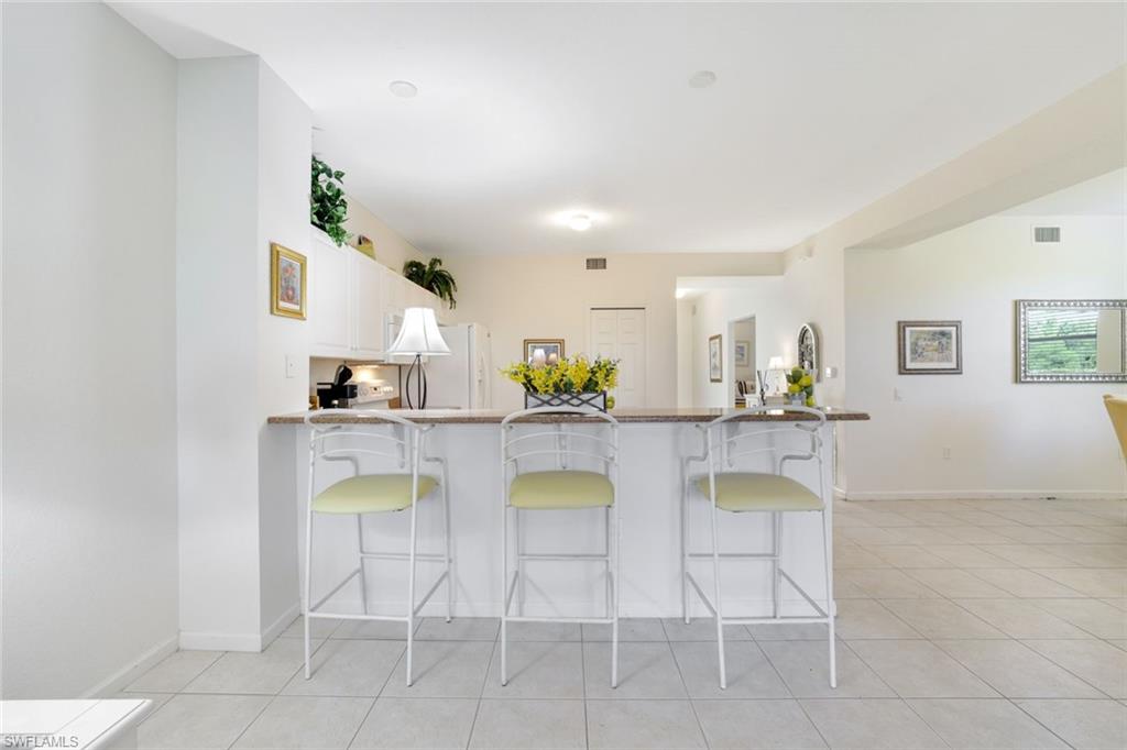 10049 Heather Lane, Unit 101 Naples, FL 34119 - Photo 8 of 25 a dining room with furniture and a kitchen view