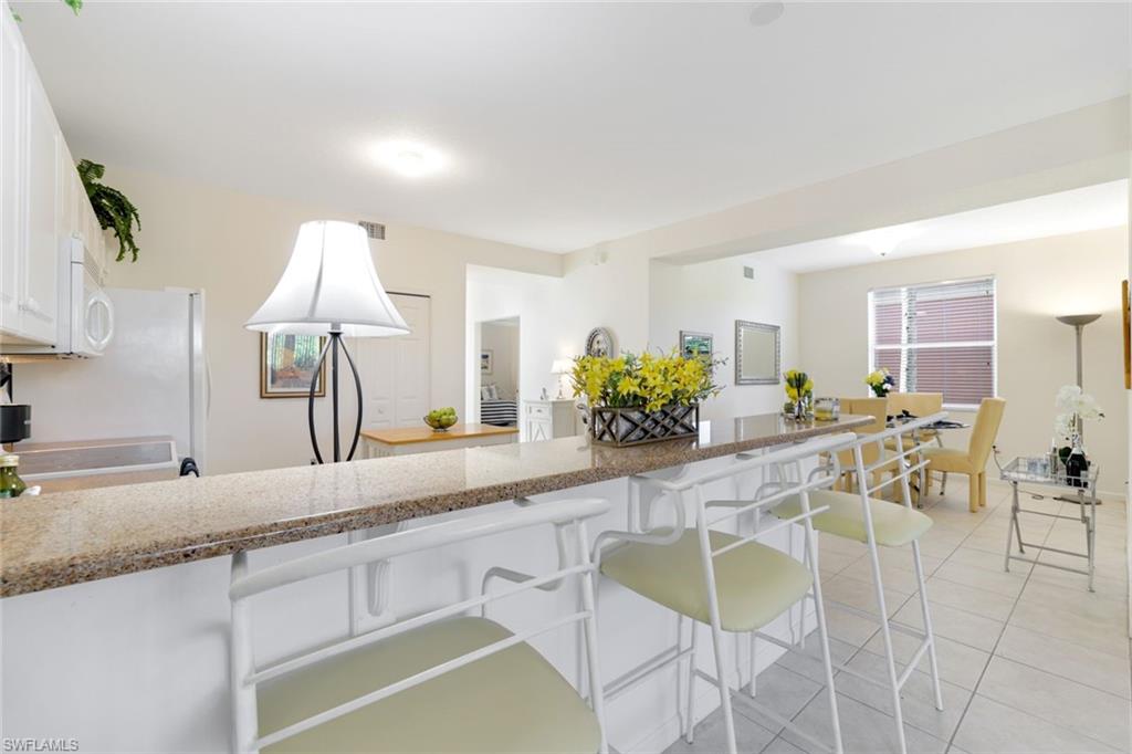 10049 Heather Lane, Unit 101 Naples, FL 34119 - Photo 9 of 25 a kitchen with stainless steel appliances kitchen island granite countertop a sink and cabinets