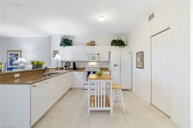 a kitchen with stainless steel appliances kitchen island granite countertop a refrigerator and a sink