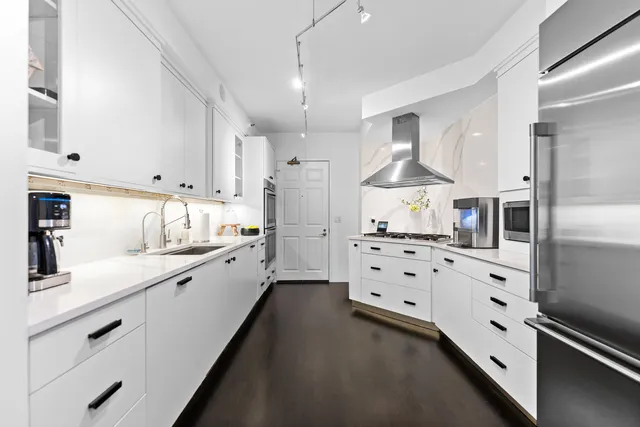 a large white kitchen with stainless steel appliances and white cabinets