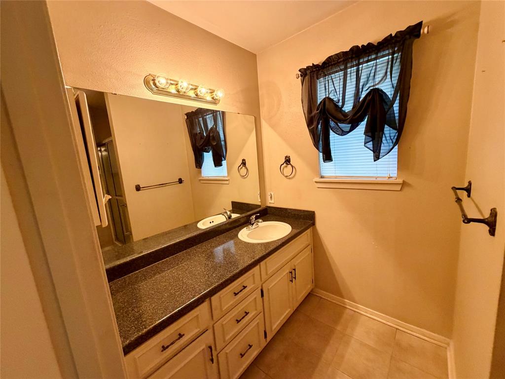 2030 Sycamore Street Paris, TX 75460 - Photo 10 of 24 Bathroom vanity with a speckled countertop, integrated sink, and cream-colored cabinetry