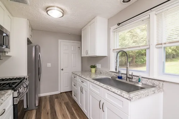 a kitchen with granite countertop a sink appliances cabinets and counter space