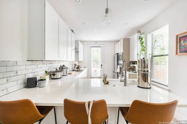 a kitchen with stainless steel appliances granite countertop a dining table chairs and a white refrigerator