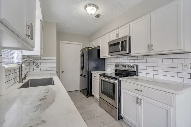 a kitchen with granite countertop a sink stove and refrigerator