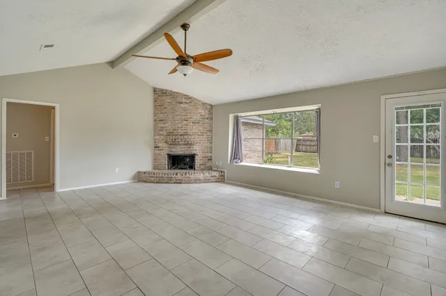 an empty room with windows and fireplace