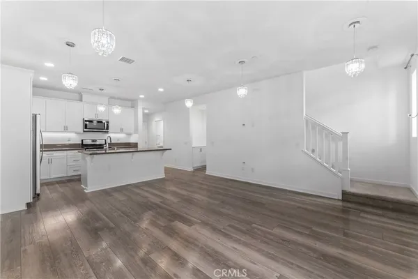 a view of kitchen with kitchen island a sink wooden floor and white stainless steel appliances