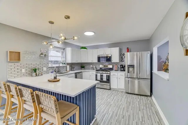 a kitchen with stainless steel appliances granite countertop a refrigerator a stove top oven a sink dishwasher and white cabinets with wooden floor
